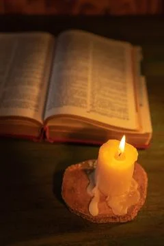 Close up with selective focus of a candle with an open bible behind it Foto stock
