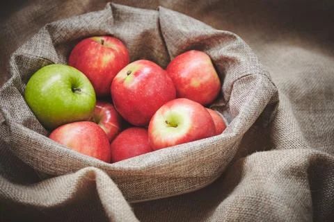 Close-up with selective focus of fresh apples in basket cover with burlap Fotos Stock
