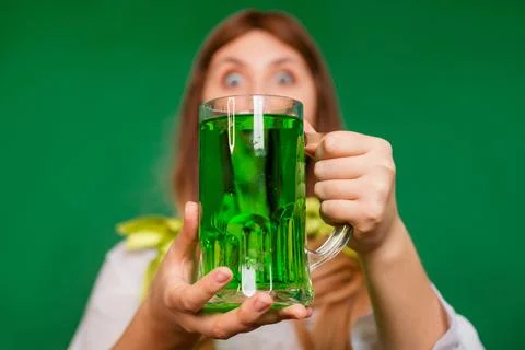 Close up, selective focus of a mug with green beer in the hands of a waitress Stock Photos