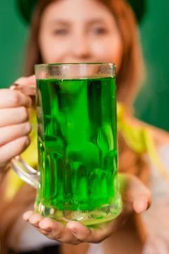 Close up, selective focus of a mug with green beer in the hands of a waitress Stock Photos