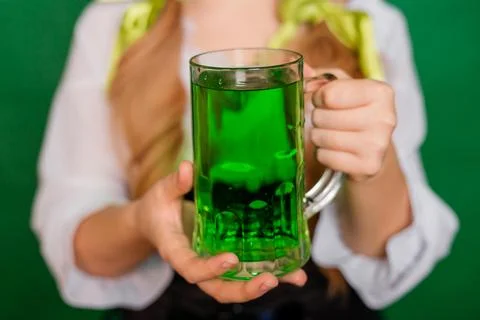 Close up, selective focus of a mug with green beer in the hands of a waitress Stock Photos