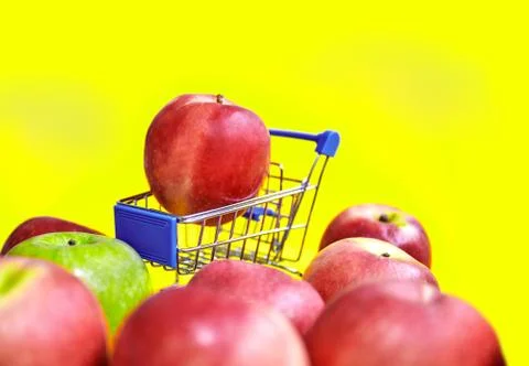 Close-up, Selective focus red apple on mini shopping cart on yellow background Foto stock