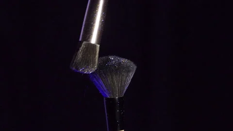 Close up selective focus shot of shimmer powder being shaken off makeup brush Stock Footage 228607946