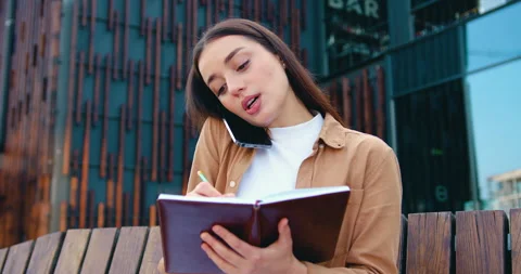 Close up of self employed female making phone call on mobile phone and taking Stock Footage 316314919