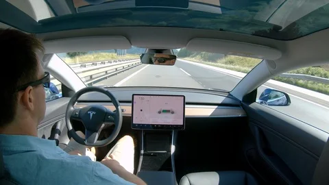 CLOSE UP: Self navigating Tesla on cruise control drives passenger down highway Stock Footage 114669648
