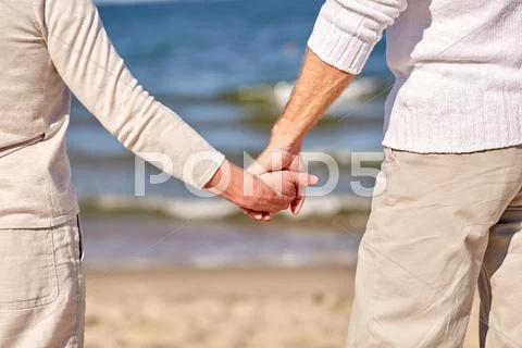 Close up of senior couple holding hands on beach Stock Photos