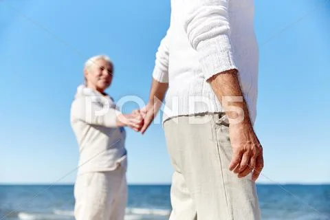 Close up of senior couple holding hands on beach Stock Photos