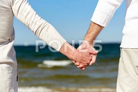 Close up of senior couple holding hands on beach Stock Photos