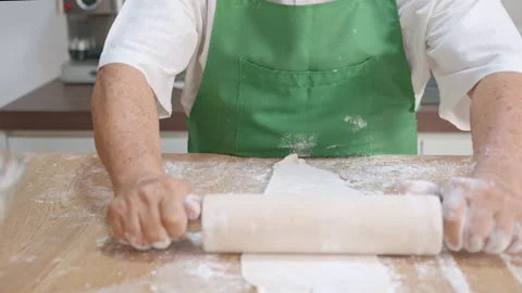 Close up senior hands holding rolling pin, kneading and rolling on dough Stock Footage 142672882