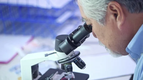 Close up on senior lab scientist looking into microscope. Stock Footage 92394892