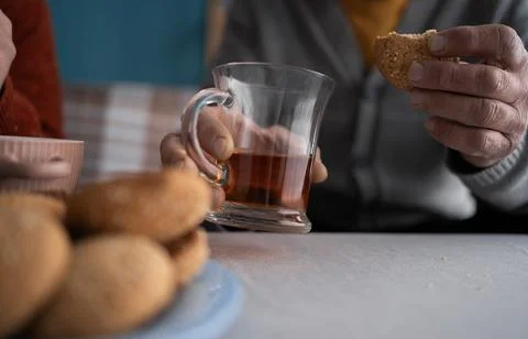 Close-up of senior male hands while son visiting him at home and drinking t.. Stock Photos