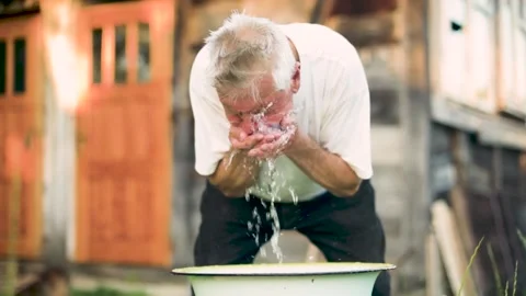 Close up of a senior man refreshing himself at a water stream Stock Footage 134959477