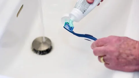 Close up of Senior Putting Toothpaste on Toothbrush Stock Footage 332254153