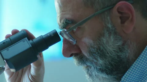 Close-Up of Senior Scientist Using Laboratory Microscope Stock Footage 247100541