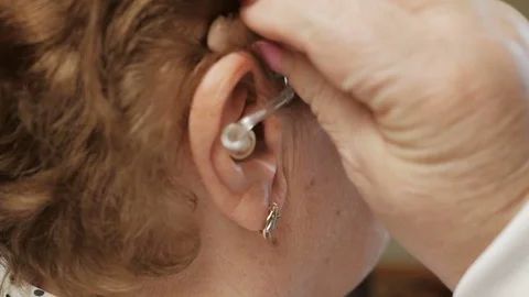 Close up of a senior woman inserting a hearing aid in her hear.  Stock Footage 85414331
