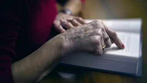 Close up on senior woman using  finger  on book  while reading Stock Footage 167127053