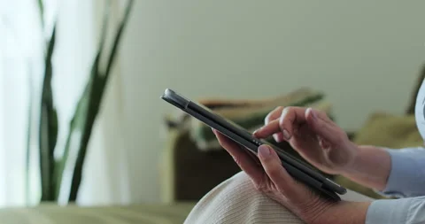 Close up. Senior woman using TabletPC on sofa in living room. 库存影片 334044729