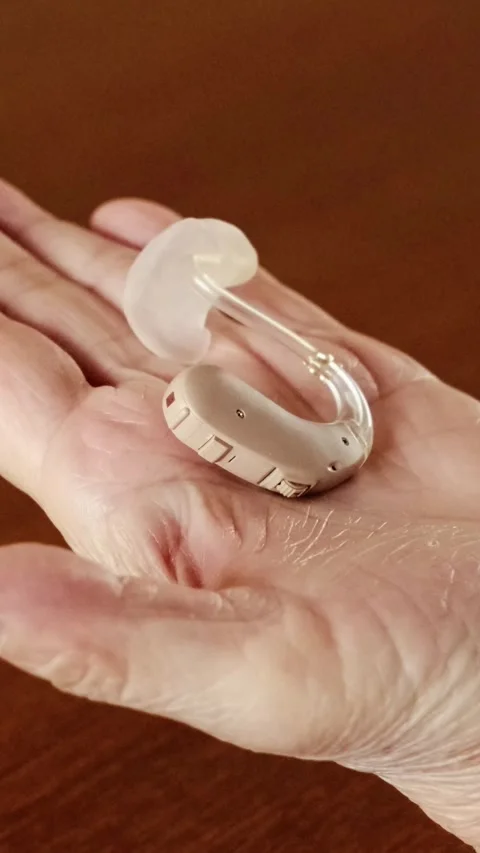 Close-up of senior woman's hand gently holding a beige hearing aid. Stock Footage 313925864