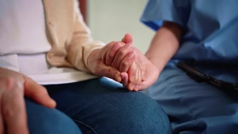 Close-up of a senior womans hand held by a nurse in blue scrubs Video stock 314648644