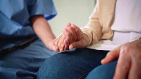 Close-up of a senior womans hand held by a nurse in blue scrubs Video stock 314648650
