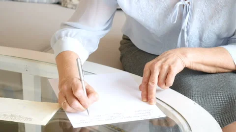 Close up, senior woman's hands writing on a piece of paper, elderly woman Stockbeeldmateriaal 99741004