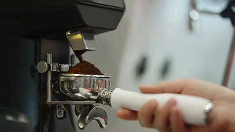 Close-up sequence of a barista grinding fresh coffee into a stainless Stock-Footage 332196733