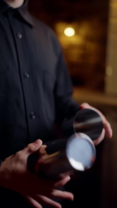 Close-up sequence of a bartender in a dark uniform handling a stainless steel Stock Footage 318541052