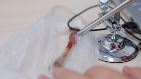 Close-up sequence of a hand using a precision tool on a specimen wrapped in Stock Footage 318709149