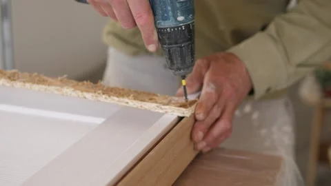 Close-up sequence of hands using cordless drill to fasten corner joint on Stock Footage 344872256