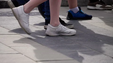 Close-up sequence showing a group of people walking on an outdoor paved walkway Stock Footage 312677127
