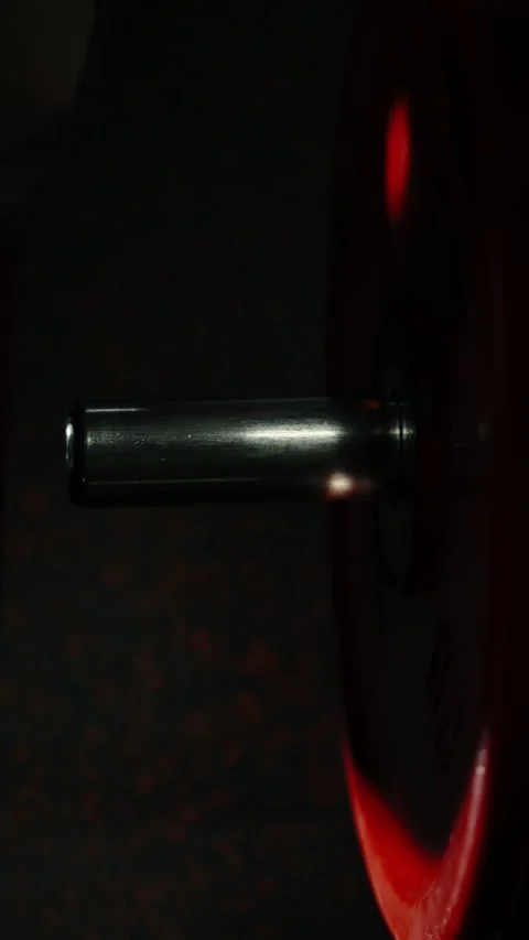 Close-up sequence showing a hand loading a red weight plate onto a polished 库存影片 329557486
