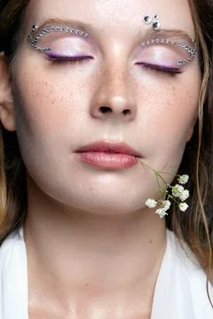 Close up of serene female model posing with rhinestone eye embellishments a.. Stock Photos