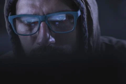 Close-up of serious computer hacker wearing eyeglasses and hood Foto stock
