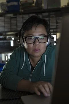 Close up serious female computer programmer working at laptop wearing headphones Stockfoto's