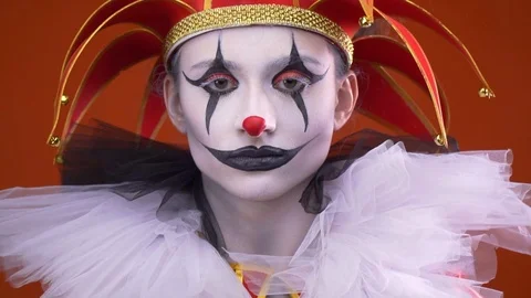 Close up of a serious female jester with makeup and a hat while a balloon is Stock Footage 104545982