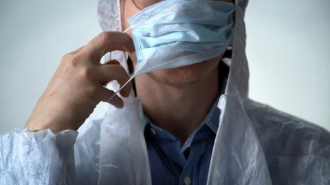 Close up. Serious man in a white protective suit on red background puts medicine Stock Footage 127481769