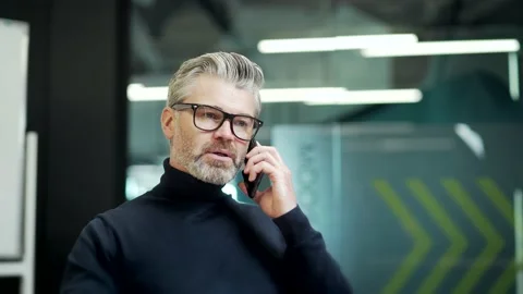Close up of serious mature gray haired bearded businessman in glasses talking on Stock Footage 232580926