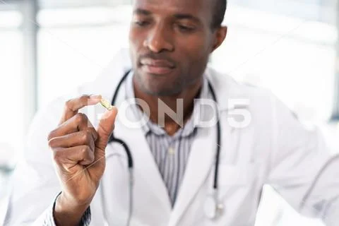 Close up of serious medical worker that staring at capsule Stock Photos