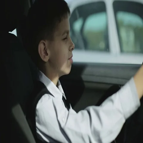 Close up. Serious schoolboy is talking on the mobile phone sitting in car. Stock Footage 69302285