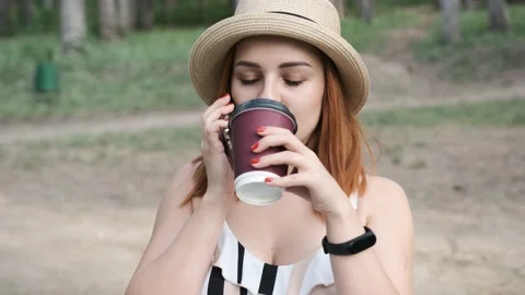 Close up of a serious young woman with a hat on her head that is drinking a cup  Stock Footage 138813053
