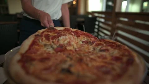 Close-up of server holding slice of freshly baked pepperoni pizza, with cozy Видео 294946104