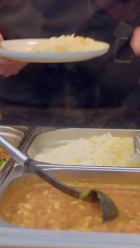 Close-up of server scooping steamed rice onto a plate at buffet counter Видео 336535683