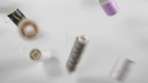 Close up of a set of bouncing bobbins of coloured thread dropped from above Stock Footage 89187056