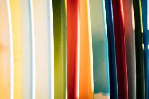 Close up Set of different color surf boards in a stack on sandy beach for ren 库存照片