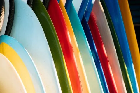 Close up Set of different color surf boards in a stack on sandy beach for ren Stock Photos