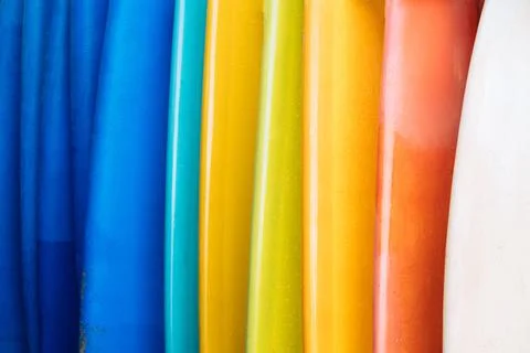Close up Set of different color surf boards in a stack on sandy beach for ren Stock Photos