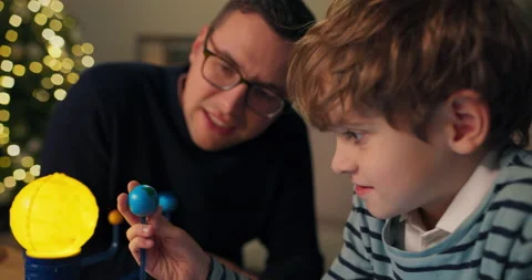 Close-up of seven-year-old boy and dad, who are considering model of the solar Stockbeeldmateriaal 210484062