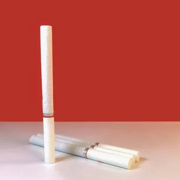 Close-up of several cigarettes with a white filter lying on a table on a whit Stock Photos