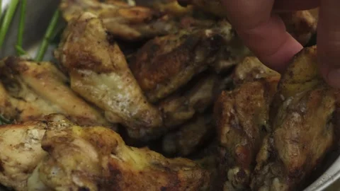 Close-up of several grilled chicken wings ready to eat and grabbing with the Stock Footage 170018334
