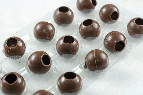 Close up of several milk chocolate shells shaped like balls inside the mold. Stock Photos